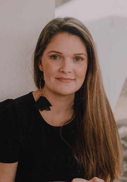 A headshot of Carole McDaniel, white female with long brown hair and wearing a black shirt smiling into camera.